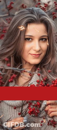 A Woman In A Grey Sweater Is Holding A Branch With Red Berries GIF