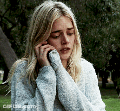 A Woman In A Grey Sweater Is Talking On Her Cell Phone GIF