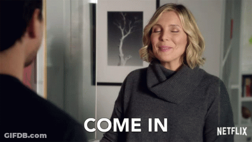 A Woman In A Grey Sweater Says Come In In A Netflix Ad GIF