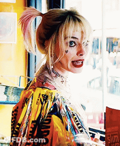 A Woman In A Harley Quinn Costume Stands In Front Of A Window . GIF