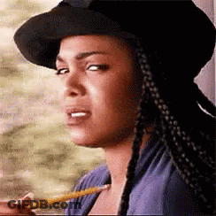 A Woman In A Hat Is Holding A Pencil In Her Mouth . GIF