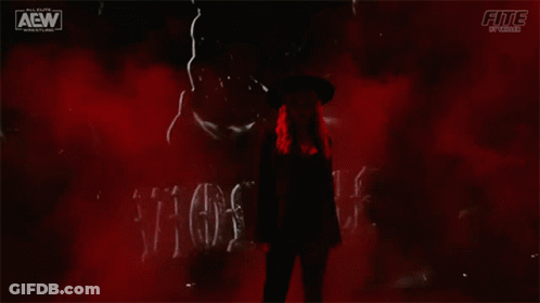 A Woman In A Hat Is Standing In Front Of A Sign That Says Violence . GIF