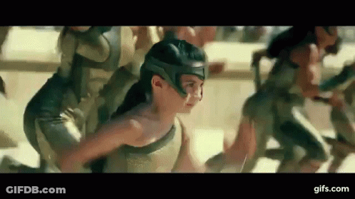 A Woman In A Helmet Is Running With A Group Of People In Armor . GIF