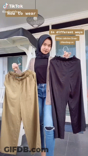 A Woman In A Hijab Is Holding A Pair Of Pants GIF