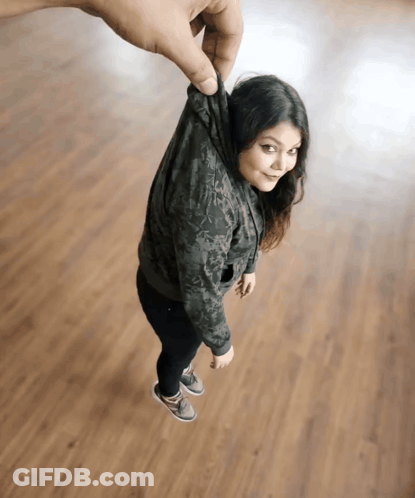 A Woman In A Hoodie Is Being Held Up By A Man 'S Hand GIF