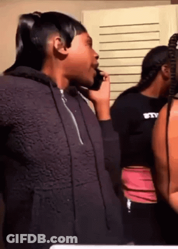 A Woman In A Hoodie Is Talking On A Cell Phone . GIF