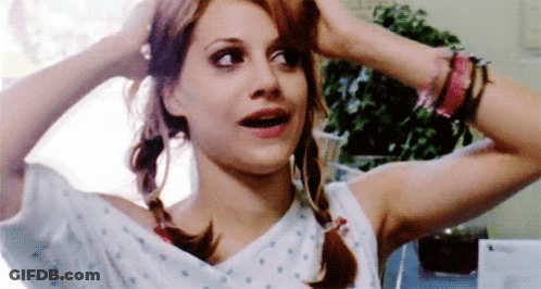 A Woman In A Hospital Gown Is Holding Her Hair In Pigtails And Making A Funny Face . GIF