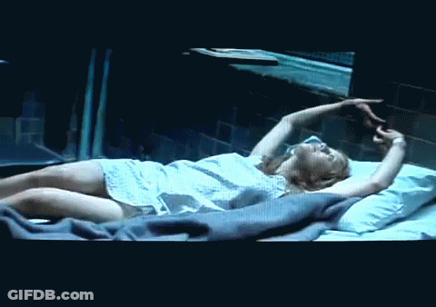 A Woman In A Hospital Gown Is Laying On A Bed GIF