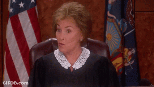 A Woman In A Judge 'S Robe Is Giving A Thumbs Up In Front Of An American Flag GIF