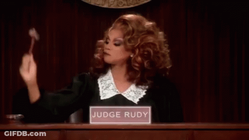 A Woman In A Judge 'S Robe Is Holding A Gavel In A Courtroom And Giving The Middle Finger . GIF