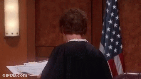 A Woman In A Judge 'S Robe Is Sitting At A Desk In A Courtroom . GIF