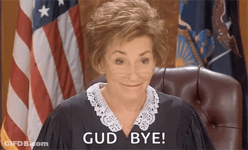 A Woman In A Judge 'S Robe Is Sitting In Front Of An American Flag And Saying Good Bye . GIF