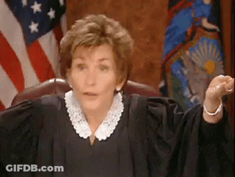 A Woman In A Judge 'S Robe Is Sitting In Front Of An American Flag In A Courtroom . GIF