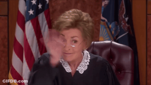A Woman In A Judge 'S Robe Is Waving Her Hand In Front Of An American Flag GIF