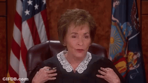 A Woman In A Judge 'S Robe Laughs In Front Of An American Flag GIF