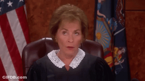 A Woman In A Judge 'S Robe Sitting In Front Of An American Flag GIF