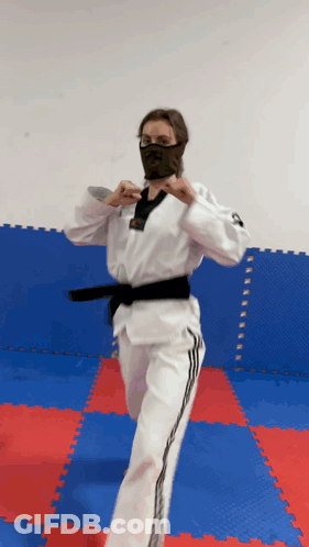 A Woman In A Karate Uniform Is Wearing A Black Mask GIF