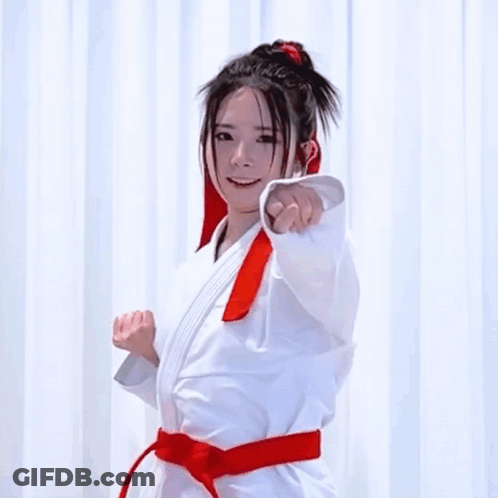 A Woman In A Karate Uniform With A Red Belt GIF