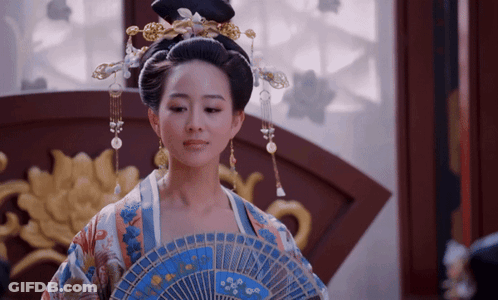 A Woman In A Kimono Is Holding A Blue Fan GIF