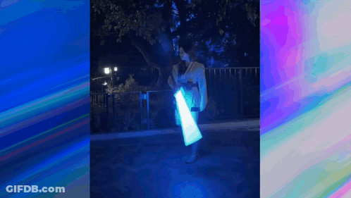 A Woman In A Kimono Is Holding A Light Saber In Her Hands . GIF