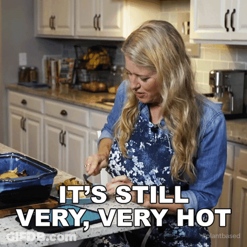 A Woman In A Kitchen With The Words " It 'S Still Very Very Hot " GIF