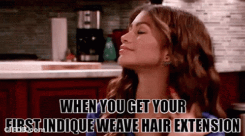 A Woman In A Kitchen With The Words When You Get Your First Indicque Weave Hair Extension GIF