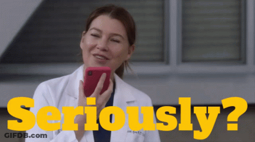 A Woman In A Lab Coat Is Holding A Cell Phone In Front Of The Words Seriously ? GIF