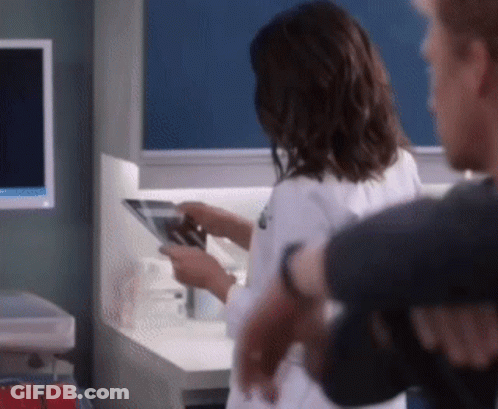 A Woman In A Lab Coat Is Looking At An X-Ray While Standing Next To A Man . GIF