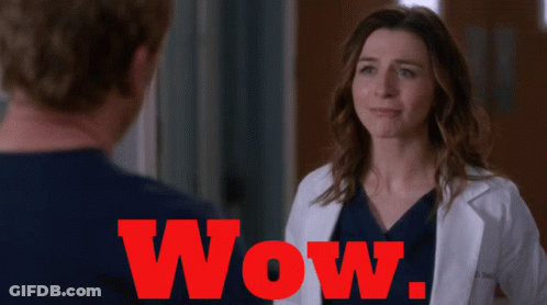 A Woman In A Lab Coat Is Standing Next To A Man And The Word Wow Is Visible In Red GIF