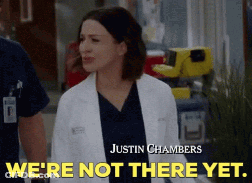 A Woman In A Lab Coat Is Standing Next To A Man In Scrubs And Says `` We 'Re Not There Yet . '' GIF