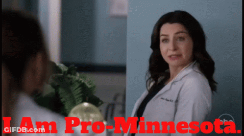 A Woman In A Lab Coat Is Standing Next To Another Woman With The Words I Am Pro-Minnesota On The Bottom GIF