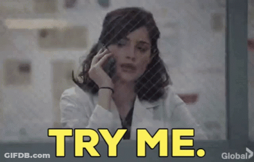 A Woman In A Lab Coat Is Talking On A Cell Phone And The Words Try Me Are Displayed . GIF