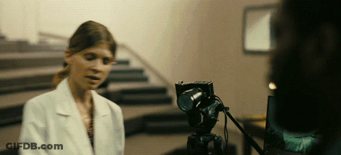 A Woman In A Lab Coat Is Talking To A Camera GIF