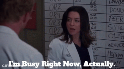 A Woman In A Lab Coat Is Talking To A Man In Front Of A White Board That Says I 'M Busy Right Now GIF