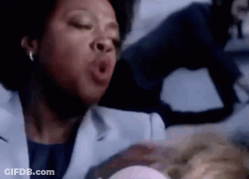 A Woman In A Lab Coat Is Yawning While Holding A Baby In Her Arms . GIF