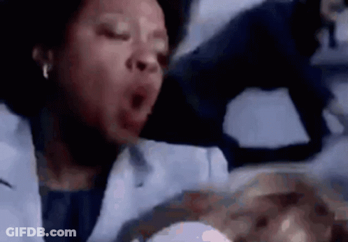 A Woman In A Lab Coat Is Yawning While Holding A Baby In Her Arms . GIF