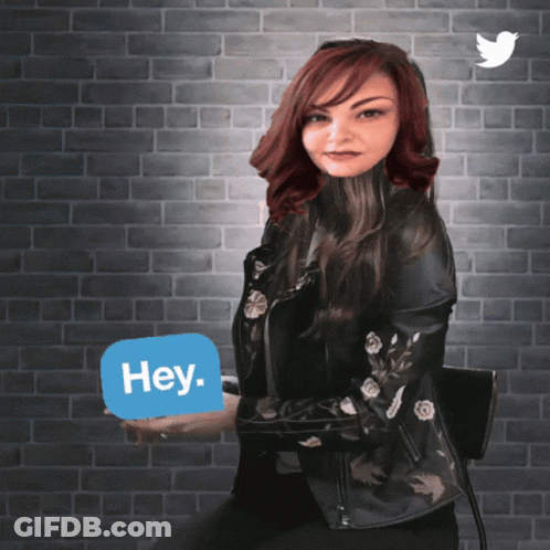 A Woman In A Leather Jacket Holds Up A Sign That Says Hey GIF