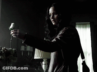 A Woman In A Leather Jacket Is Holding A Rose In Her Hand GIF