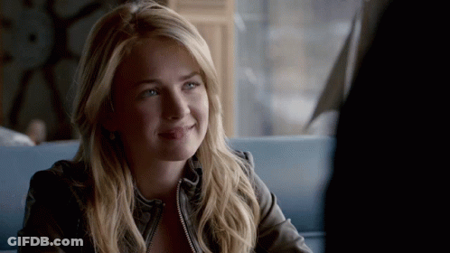 Woman In Leather Jacket Smiling At Table GIF