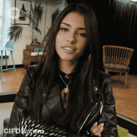A Woman In A Leather Jacket Is Smiling With A Spotify Logo In The Corner GIF