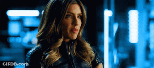 A Woman In A Leather Jacket Is Standing In A Dark Room . GIF