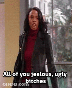 A Woman In A Leather Jacket Is Standing In Front Of A Window . GIF