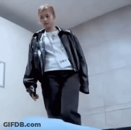 A Woman In A Leather Jacket Is Standing On A Blue Cushion . GIF