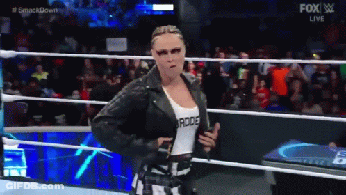 A Woman In A Leather Jacket Is Walking In A Wrestling Ring . GIF