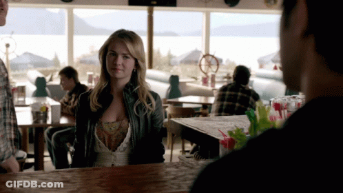 Woman In Leather Jacket Sitting At Bar Looking At Man GIF