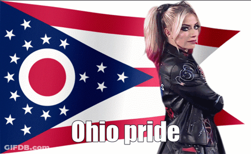 A Woman In A Leather Jacket Stands In Front Of An Ohio Pride Flag GIF