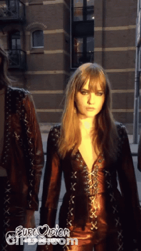 A Woman In A Leather Outfit With Eurovision Going Contest Written On The Bottom Right GIF