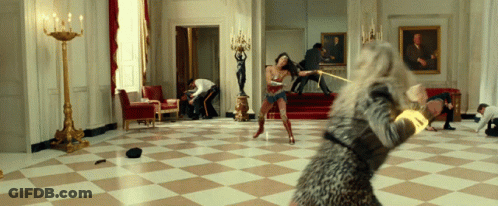A Woman In A Leopard Print Dress Is Holding A Sword In A Room GIF