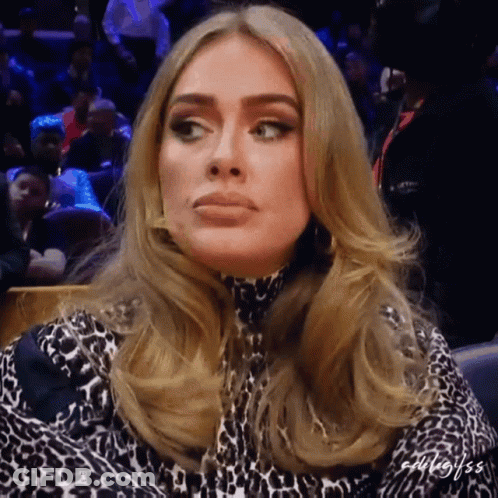 A Woman In A Leopard Print Dress Is Sitting In A Crowd Of People GIF