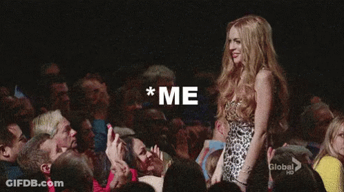 A Woman In A Leopard Print Dress Is Standing In Front Of A Crowd With Her Arm In The Air . GIF